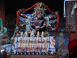 Lo Manthang Thubchen 05-3 Main Assembly Hall Hayagriva Statue To the right of Amitayus is a statue of red Hayagriva in yam-yum with his consort in the main assembly hall at Thubchen Gompa in Lo Manthang. Hayagriva, a fierce form of the compassionate Avalokiteshvara, has huge wings, three heads crowned with skulls, six arms and four legs, and a horse head in his hair, which gives him his name �horse-necked one�. Hayagriva wears a belt strung with freshly severed heads, a lion skin loincloth. In his front left hand he holds a skull cup filled with transformed blood and guts of sentient beings and in his front right hand a vajra.